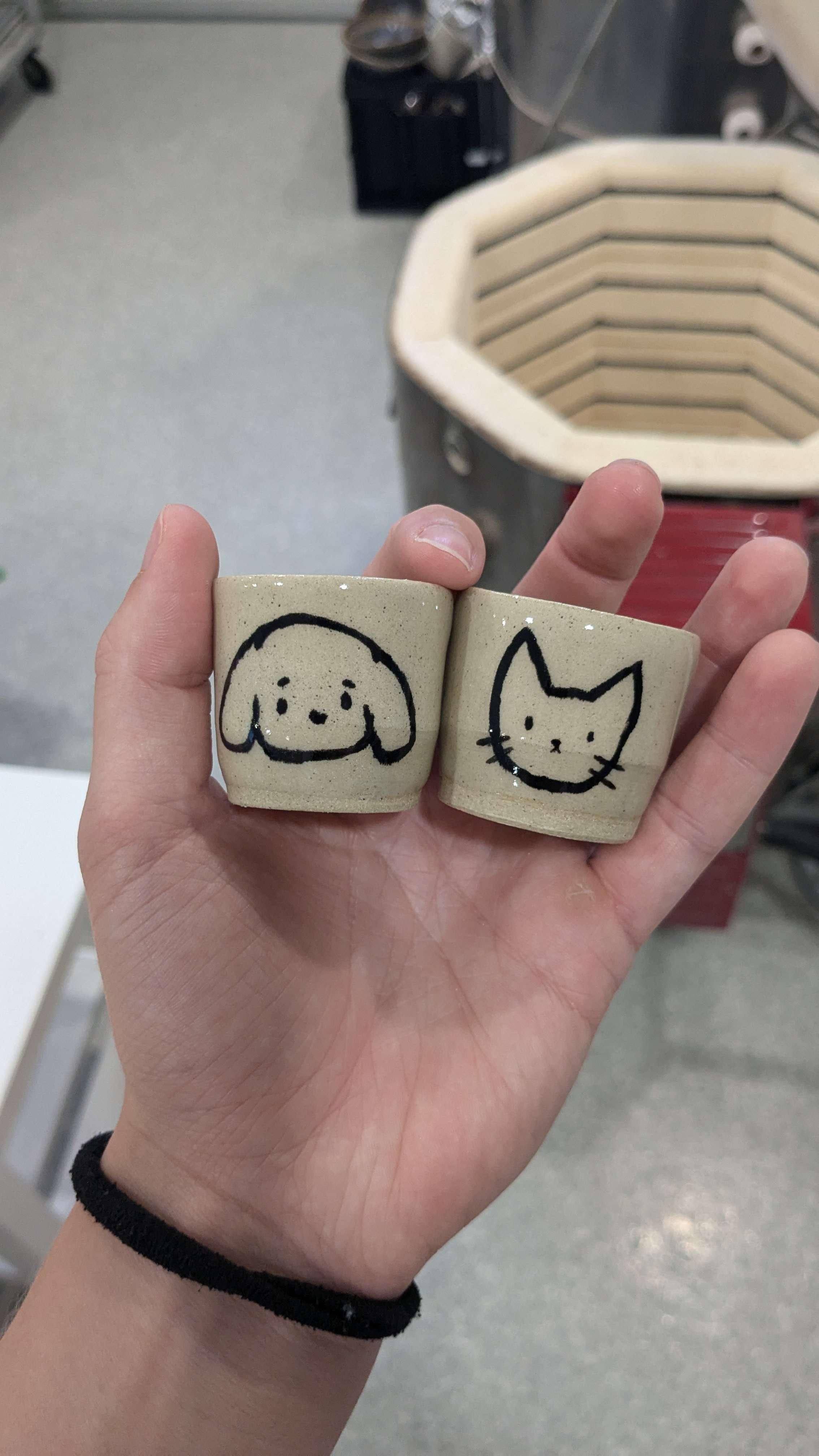 Two shotglasses, one wiht a cat the other with a dog 